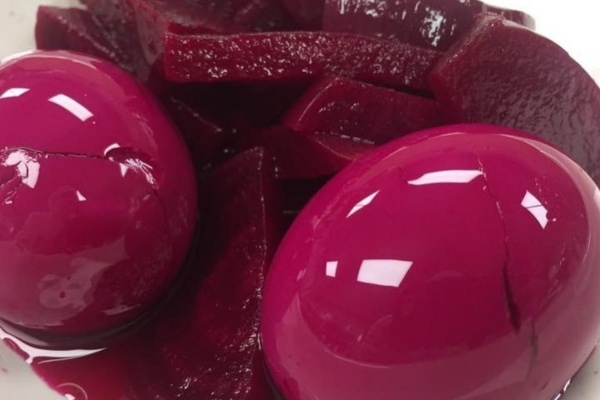 Two beets are sitting in a bowl with sliced beets.