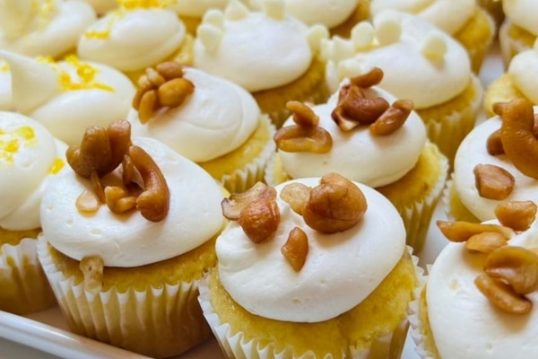 A tray of cupcakes with white frosting and cashew nuts, perfect for catering events.