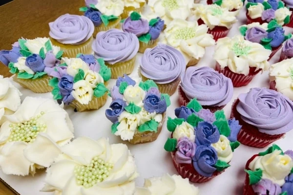 A tray of cupcakes adorned with purple and white flowers, perfect for desserts.