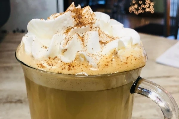 Latte topped with whipped cream and a hint of cinnamon.