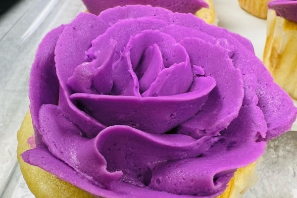 Cupcakes adorned with a purple rose-shaped frosting.