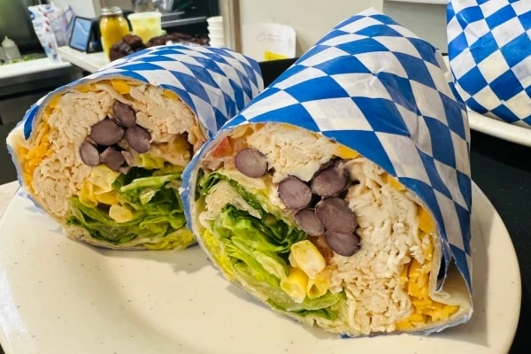 Chicken wrap sandwiches wrapped with blue and white checkered paper.
